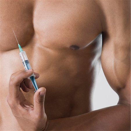 Mid section view of a young man holding a syringe against his chest Stock Photo - Premium Royalty-Free, Code: 630-01493075