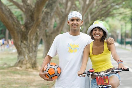 simsearch:630-01491738,k - Portrait of a young man standing with a young woman riding a bicycle Stock Photo - Premium Royalty-Free, Code: 630-01708058