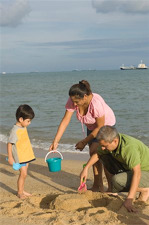 Mid adult couple making a sand castle on the beach with their son Stock Photo - Premium Royalty-Free, Code: 630-01708167