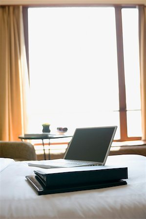 Ordinateur portable avec des fichiers sur le lit dans une chambre d'hôtel Photographie de stock - Premium Libres de Droits, Code: 630-01708433