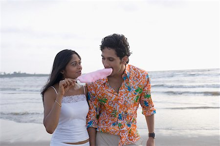 Young woman holding a cotton candy and a young man eating it Stock Photo - Premium Royalty-Free, Code: 630-01708626