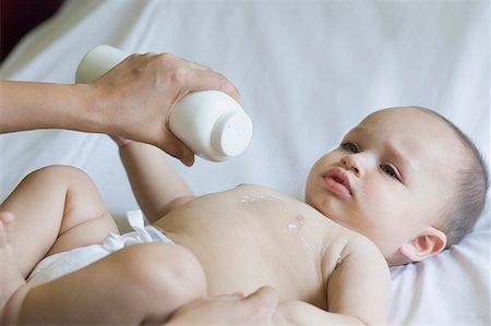 Close-up of a person's hand putting talcum powder on the chest of a baby Stock Photo - Premium Royalty-Free, Code: 630-01709614