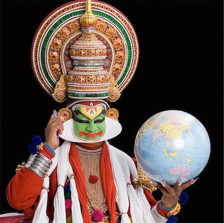 Portrait of a Kathakali dance performer holding a globe and a mobile phone Stock Photo - Premium Royalty-Free, Code: 630-01709976