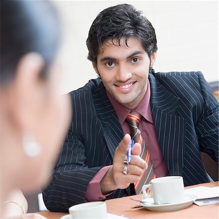 Portrait of a businessman pointing forward and smiling Stock Photo - Premium Royalty-Free, Code: 630-01874072