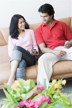 Jeune couple assis avec les téléphones mobiles sur un divan et souriant Photographie de stock - Premium Libres de Droits, Code: 630-01874569