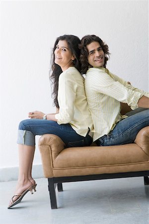 Young couple sitting back to back and smiling Stock Photo - Premium Royalty-Free, Code: 630-01874697