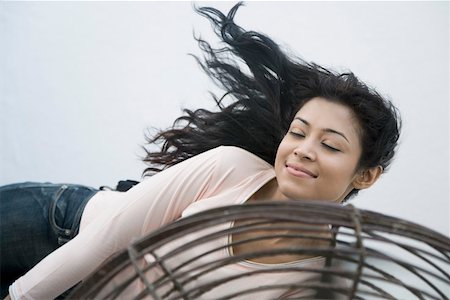 Young woman lying in front of a fan Stock Photo - Premium Royalty-Free, Code: 630-01874722