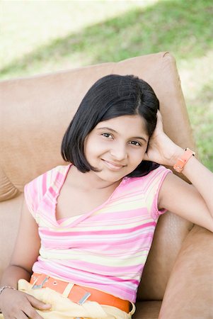 Portrait of a girl sitting in an armchair and smiling Stock Photo - Premium Royalty-Free, Code: 630-01874879