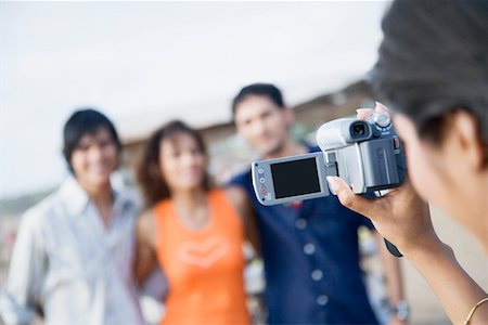 Close-up of a woman taking a video of her three friends Stock Photo - Premium Royalty-Free, Code: 630-01875094