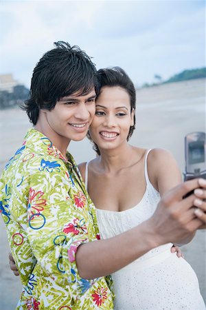 simsearch:6108-05873097,k - Side profile of a young couple taking a photograph of themselves with a mobile phone Stock Photo - Premium Royalty-Free, Code: 630-01875207