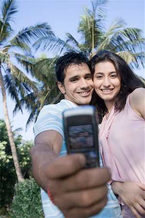 simsearch:630-01876693,k - Low angle view of a young couple taking a picture of themselves with a mobile phone and smiling Stock Photo - Premium Royalty-Free, Code: 630-01875404