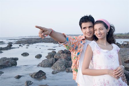 simsearch:630-01296756,k - Young man standing with a young woman on the coast and pointing forward Foto de stock - Sin royalties Premium, Código: 630-01875491