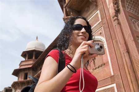 simsearch:630-01872552,k - Low angle view of a young woman holding a digital camera and smiling, Taj Mahal, Agra, Uttar Pradesh, India Stock Photo - Premium Royalty-Free, Code: 630-01876314