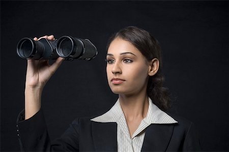 Close-up of a businesswoman holding binoculars in front of her face Stock Photo - Premium Royalty-Free, Code: 630-01876499