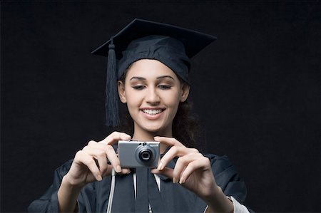 simsearch:630-01876527,k - Gros plan d'un jeune diplômé de femme tenant un appareil photo numérique Photographie de stock - Premium Libres de Droits, Code: 630-01876505
