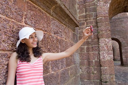 Young woman talking a photograph with a mobile phone and smiling, Goa, India Stock Photo - Premium Royalty-Free, Code: 630-01876680
