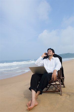 Businessman sitting in an armchair on the beach and talking on a mobile phone Stock Photo - Premium Royalty-Free, Code: 630-01877049