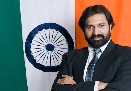 Portrait of a mid adult man standing with his arms crossed in front of an Indian flag Stock Photo - Premium Royalty-Free, Code: 630-01877093