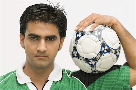 Portrait of a young man carrying a soccer ball on his shoulder Stock Photo - Premium Royalty-Free, Code: 630-01877120