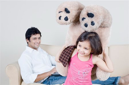 Close-up of a girl holding a teddy bear and her father sitting behind her Foto de stock - Sin royalties Premium, Código: 630-01877164