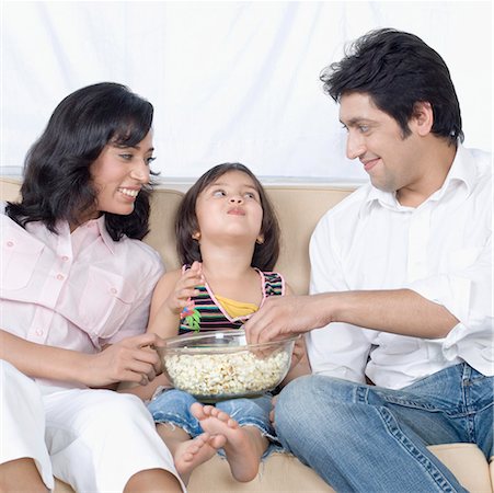 Family sitting on a couch and eating popcorn Stock Photo - Premium Royalty-Free, Code: 630-01877175
