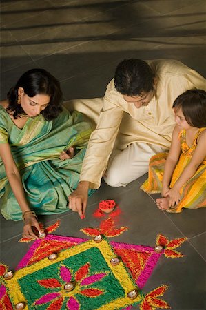 High angle view of a mid adult man and a young woman making rangoli with their daughter Foto de stock - Sin royalties Premium, Código: 630-01877203