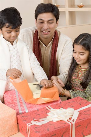 simsearch:630-01873032,k - Young man sitting with his children and opening diwali gifts Stock Photo - Premium Royalty-Free, Code: 630-01877217