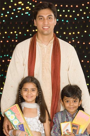 Portrait of a young man standing with his son and daughter and holding diwali crackers Foto de stock - Sin royalties Premium, Código: 630-01877228