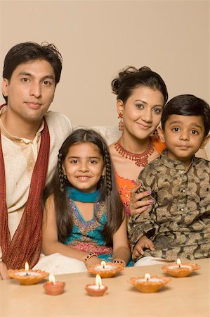 Portrait of a young couple sitting together with their son and daughter behind diwali lamps Foto de stock - Sin royalties Premium, Código: 630-01877275