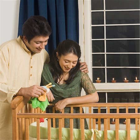 Young woman and a mid adult man looking inside a crib and smiling Stock Photo - Premium Royalty-Free, Code: 630-01877338