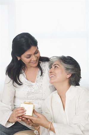 Mid adult woman giving a gift to her mother and smiling Stock Photo - Premium Royalty-Free, Code: 630-01877520