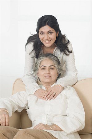 Portrait of a mature woman sitting on a couch and her daughter embracing her from behind Stock Photo - Premium Royalty-Free, Code: 630-01877523