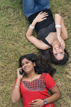 simsearch:630-01491738,k - High angle view of two young women lying on the grass talking on mobile phones and smiling Stock Photo - Premium Royalty-Free, Code: 630-01877785