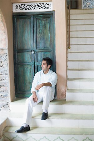 Young man sitting in front of a door Stock Photo - Premium Royalty-Free, Code: 630-01872319
