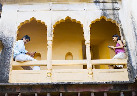 rajasthan clothes for women - Couple sitting on the railing of palace and using cell phones, Neemrana Fort Palace, Neemrana, Alwar, Rajasthan, India Stock Photo - Premium Royalty-Free, Code: 630-01872430