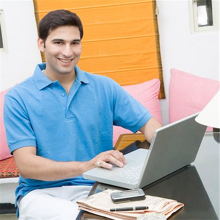 polo shirt - Portrait of a young man working on a laptop and smiling Stock Photo - Premium Royalty-Free, Code: 630-01872580