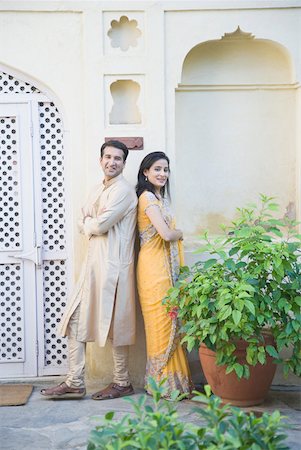 Mid adult couple standing back to back in front of a building and smiling Stock Photo - Premium Royalty-Free, Code: 630-01872910