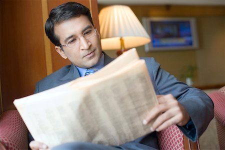 simsearch:630-01873072,k - Close-up of a businessman sitting in an armchair and reading a newspaper Stock Photo - Premium Royalty-Free, Code: 630-01873084