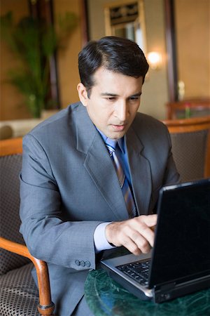 Homme d'affaires assis dans un fauteuil et travaillant sur un ordinateur portable Photographie de stock - Premium Libres de Droits, Code: 630-01873121