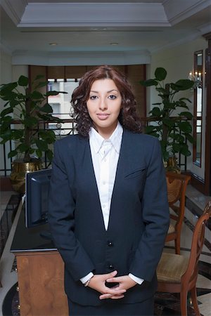 Portrait de femme réceptionniste permanent lors d'une réception de l'hôtel et souriant Photographie de stock - Premium Libres de Droits, Code: 630-01873166