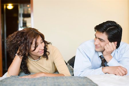 Businessman and a businesswoman lying on the bed and looking at each other Stock Photo - Premium Royalty-Free, Code: 630-01873315