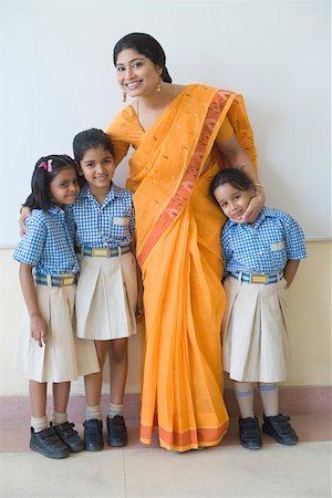 school girl skirt - Portrait of a teacher standing with three students and smiling Stock Photo - Premium Royalty-Free, Code: 630-01873534