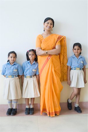 Portrait of a teacher standing with three schoolgirls and smiling Stock Photo - Premium Royalty-Free, Code: 630-01873533