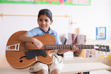 Schoolgirl sitting on a bench and playing a guitar Stock Photo - Premium Royalty-Free, Code: 630-01873641