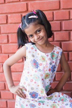 Portrait of a girl standing in front of a wall and smiling Stock Photo - Premium Royalty-Free, Code: 630-01873660