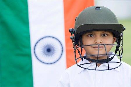 Portrait of a cricket player smiling with an Indian flag in the background Stock Photo - Premium Royalty-Free, Code: 630-01873680