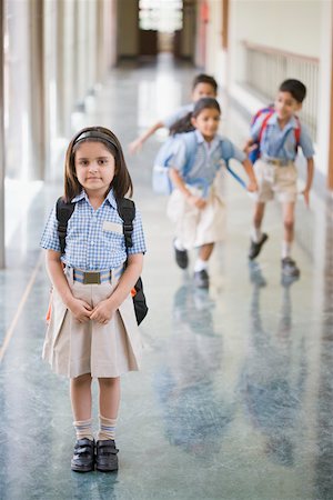 school children in uniform - Portrait of a schoolgirl standing in the corridor with three student running in the background Stock Photo - Premium Royalty-Free, Code: 630-01873763