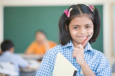 Portrait of a schoolgirl holding a pencil with a book and smiling Stock Photo - Premium Royalty-Free, Code: 630-01873784