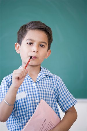 Portrait of a schoolboy holding a pencil and a book in front of a blackboard Foto de stock - Sin royalties Premium, Código: 630-01873782