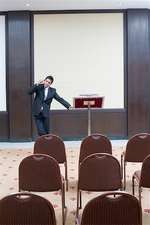 simsearch:630-01873072,k - Businessman standing at a lectern and talking on a mobile phone Stock Photo - Premium Royalty-Free, Code: 630-01873878
